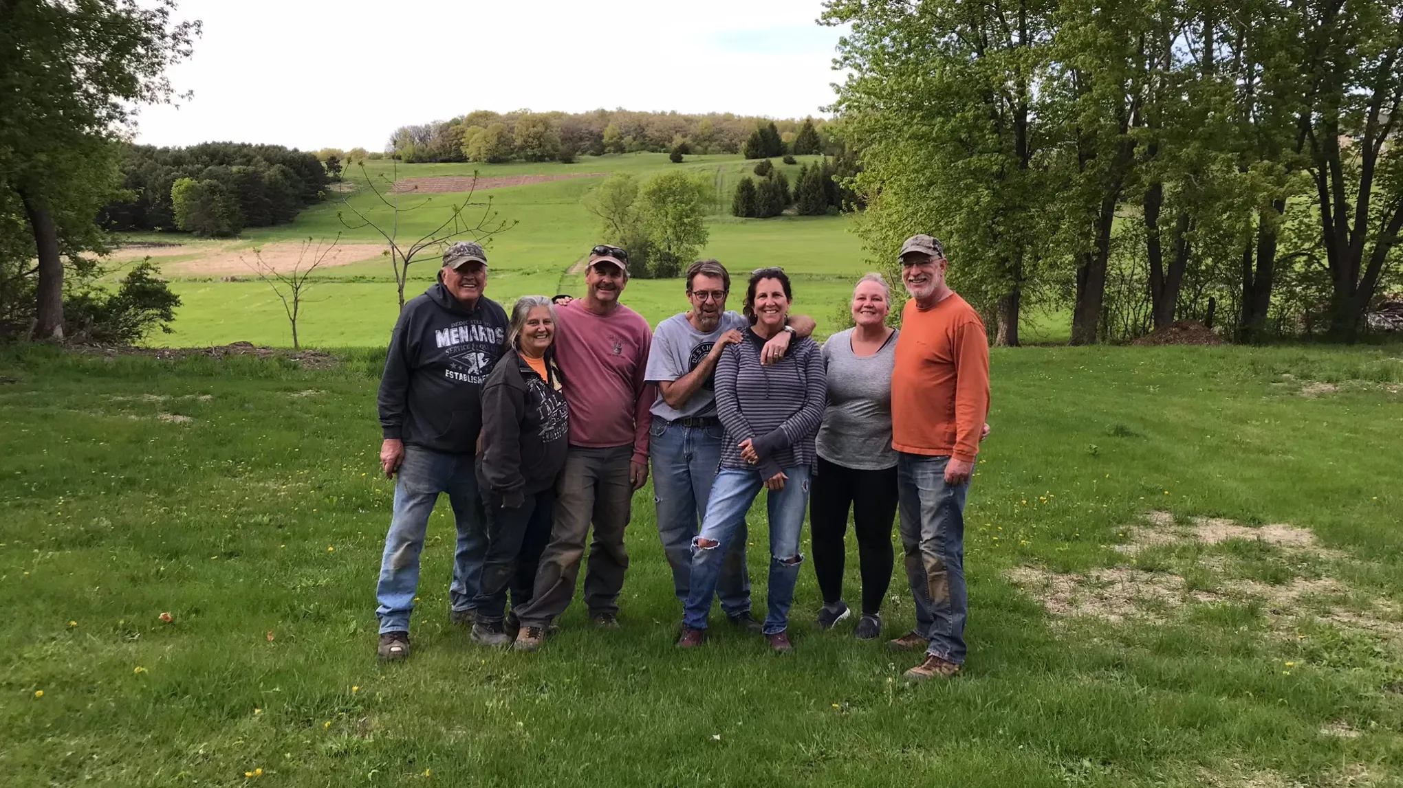 a group of people standing on top of a grass covered field